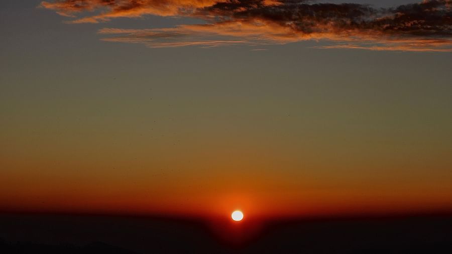 The sun sets on the horizon, casting a warm glow across the landscape, with cloud accents adding depth and texture to the sky, possibly a tranquil evening view from the resort