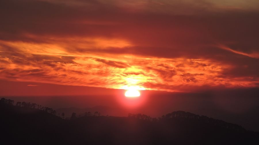 A fiery sunset paints the sky with vibrant hues, casting a warm glow over the silhouetted mountain peaks, creating a dramatic and captivating scene, possibly seen from the resort