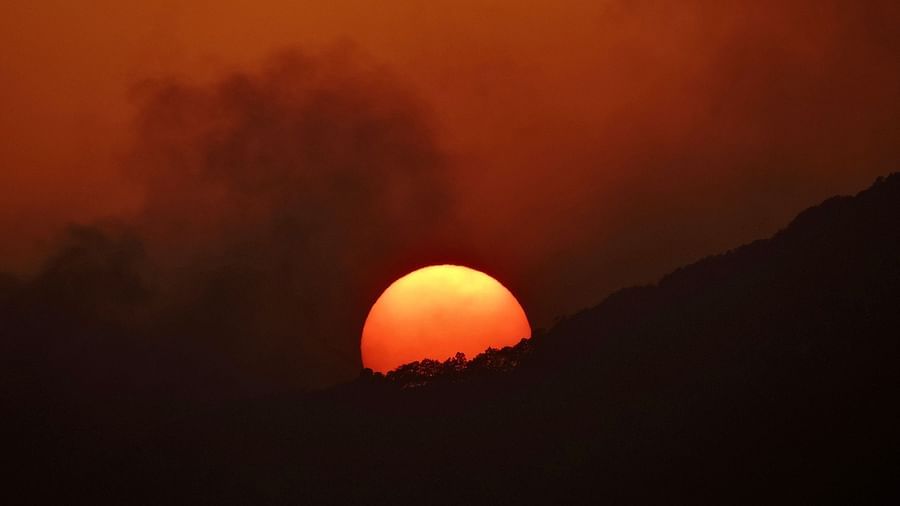 The sun dips below the horizon, setting behind a majestic mountain peak, creating a stunning silhouette against the warm glow of the setting sun, possibly a view from the resorts surroundings