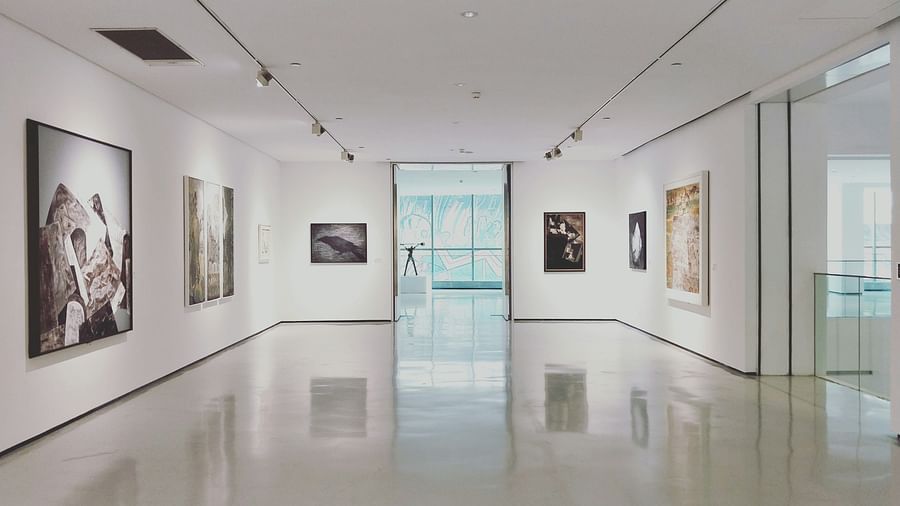 An overview of a museum with painting hung on all the walls