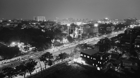 An aerial view of Indore at night with the lights on in the streets, with trees, street lights, buildings in view. 