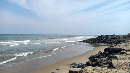 Waves crashing on a rocky beach shore on a clear day.