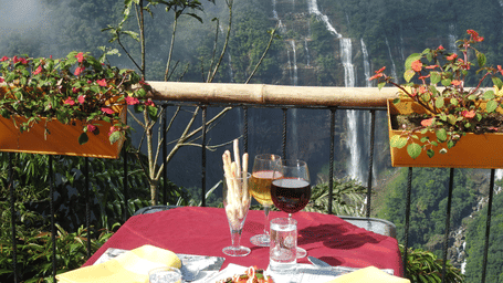 A romantic outdoor dining setup overlooking the misty Seven Sisters Waterfalls - Polo Resort Cherrapunjee
