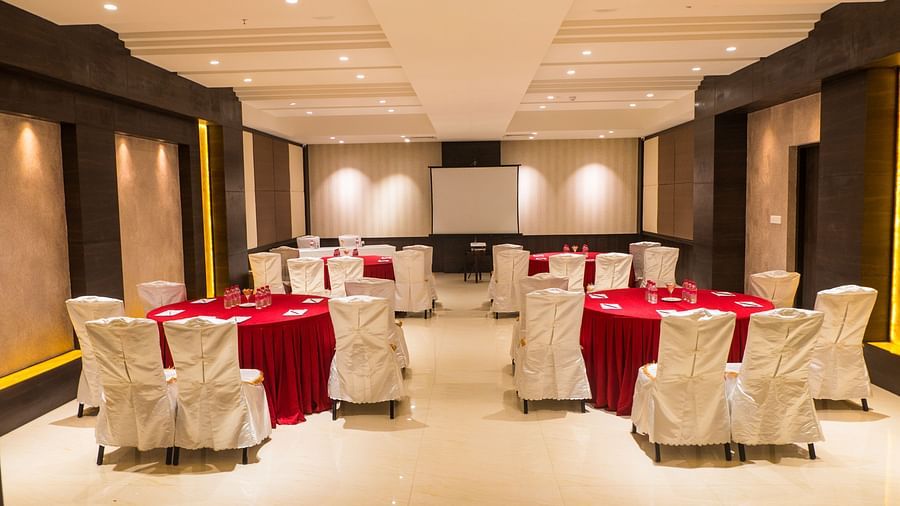 event hall with red tables and white satin chairs of ASR Parklane, Hosur