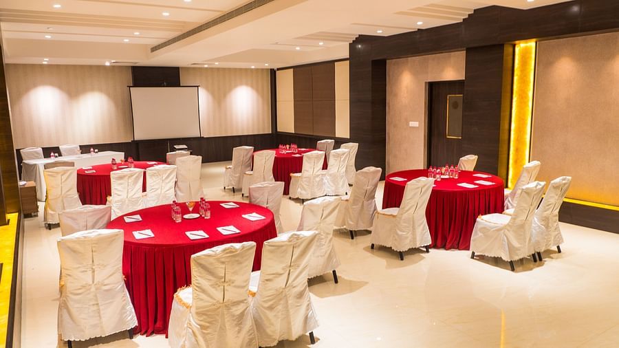 event hall with red tables and white satin chairs of ASR Parklane, Hosur