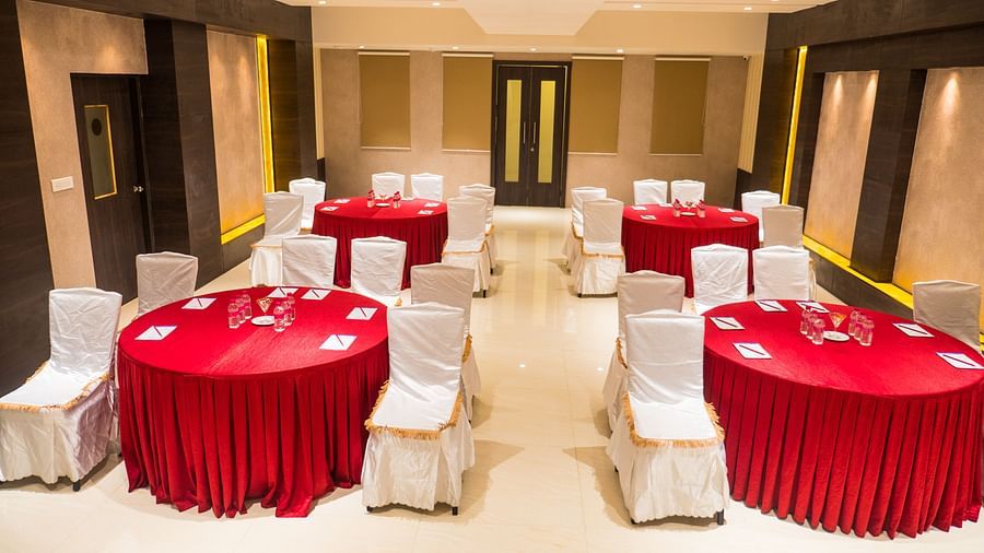 event hall with red tables and white satin chairs of ASR Parklane, Hosur