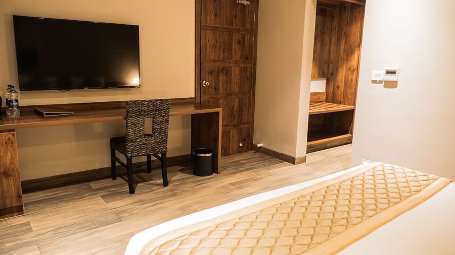 king size bed  and TV with a work desk of Queen Suite Room at Cholaa Dynasty, Kumbakonam