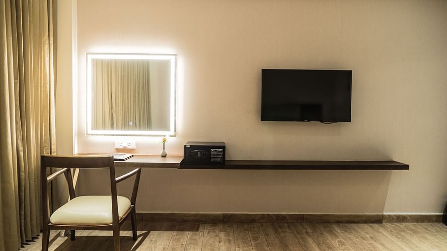 A work desk placed with a mirror and a television in Premium Room at Grand Ashok, Thanjavur.