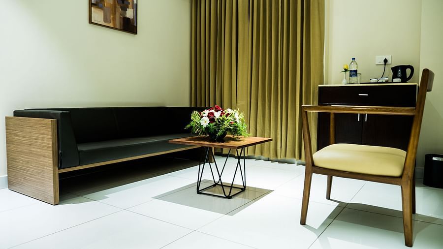 Living area of Suite with comfortable sofa placed in front of a small table at Grand Ashok, Thanjavur.