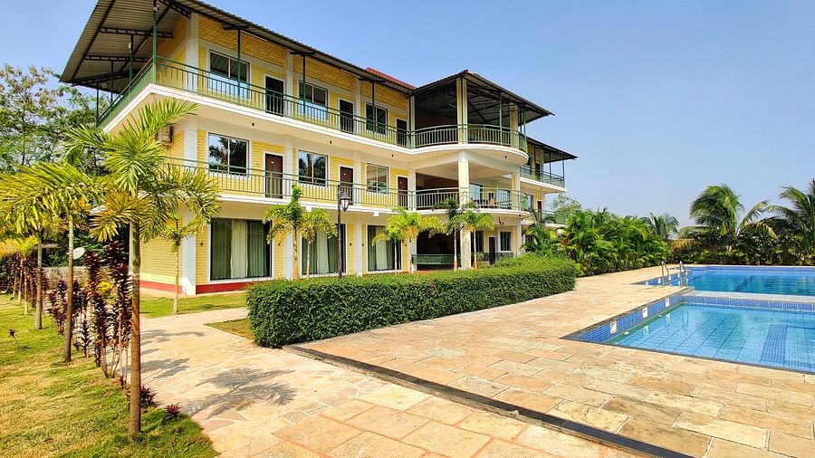 Facade of The Kanila Resort with a swimming pool and backdrop of clear sky.