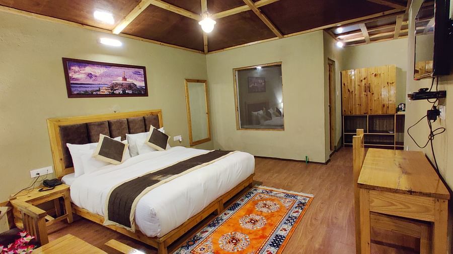 Premium Cottage at White Sands Resort, Ladakh with a king size bed, wooden furniture, and a patterned rug.
