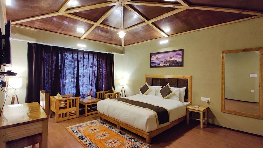 Premium Cottage at White Sands Resort, Ladakh, with a focus on the king size bed, curtains, and wooden furniture.