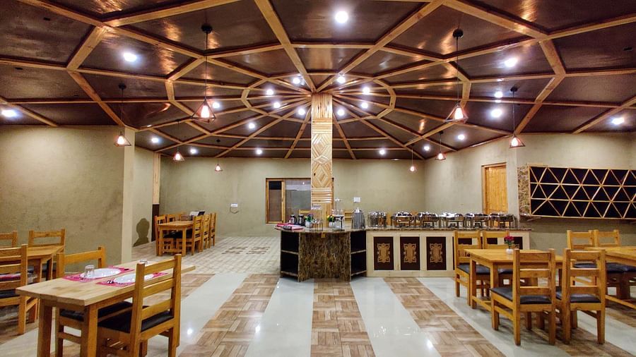 The interior of a dining area with wooden tables and chairs at White Sands Resort, Ladakh.