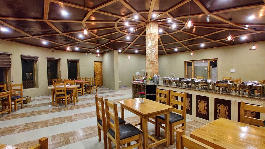The interior of a dining area at White Sands Resort, Ladakh highlighting the wooden furniture, ceiling design, and buffet area.