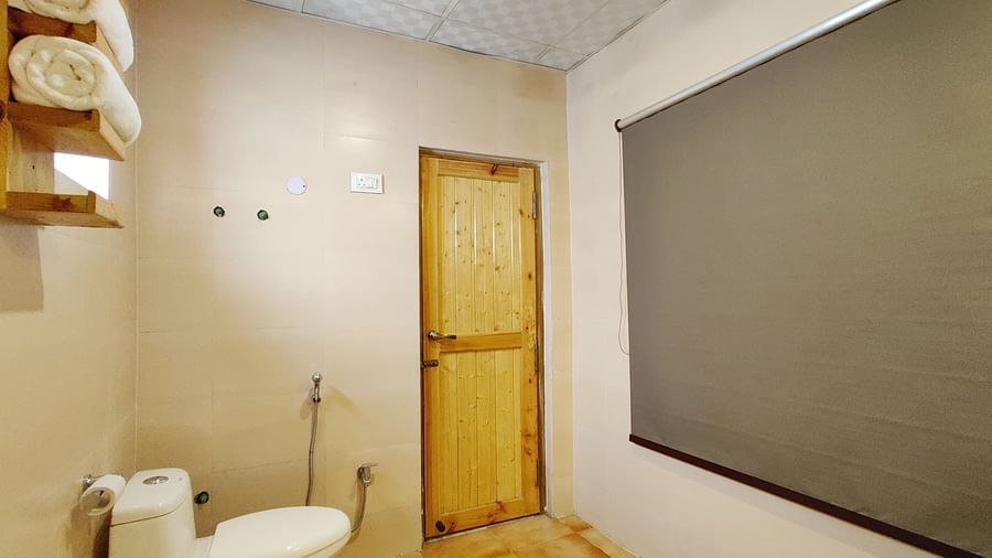 A bathroom in Premium Cottage at White Sands Resort, Ladakh, is equipped with a toilet, sink, and shower.