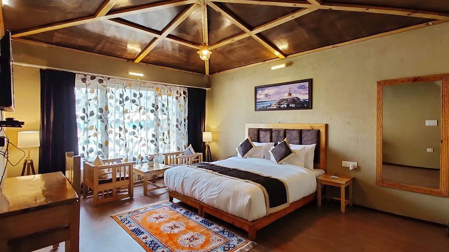 Premium Cottage at White Sands Resort, Ladakh , showcasing a king size bed, wooden accents, and a rug with a different pattern.