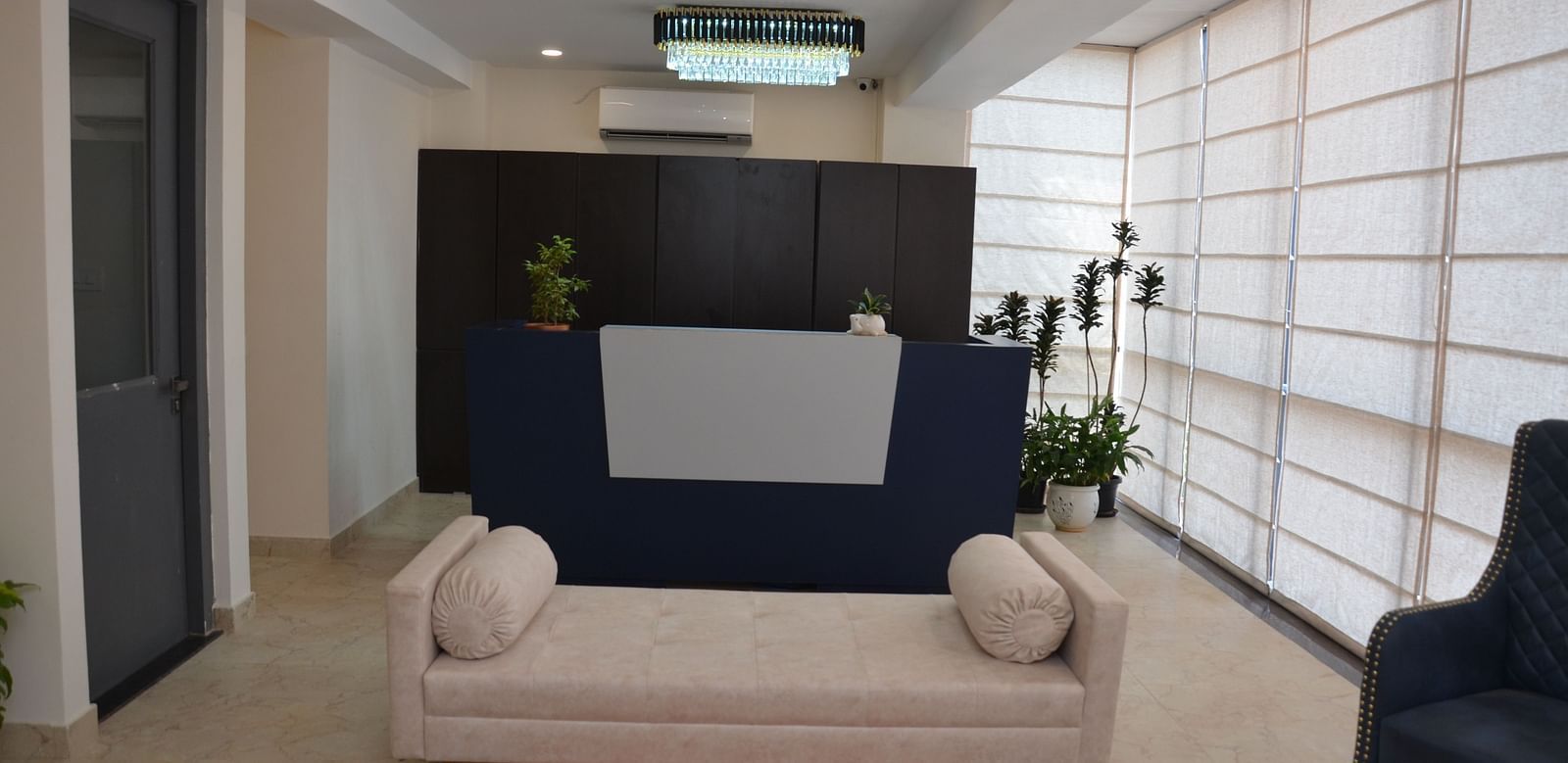 The reception area featuring a front desk in front of a white coloured couch without a backrest - Lords Eco Inn Belagavi