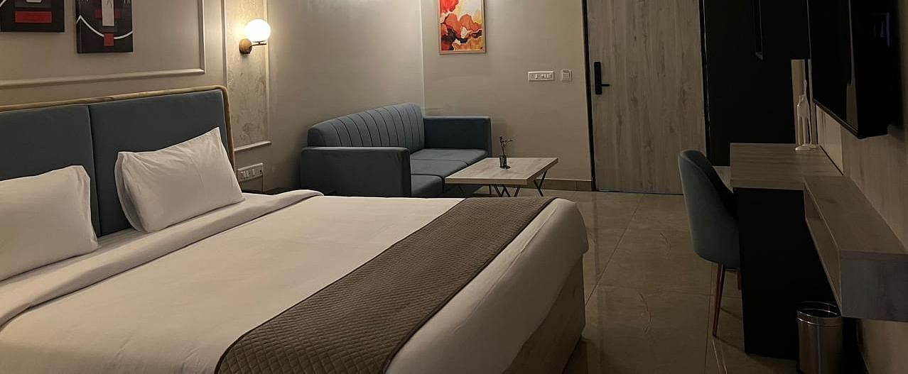 A spacious room side view featuring a large bed, furniture, a table placed against the wall, and a ceiling fan 