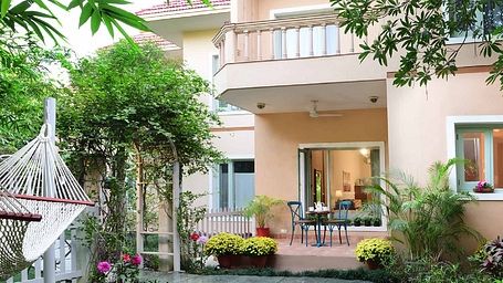 Karma Chalet's facade with a garden and paved path.