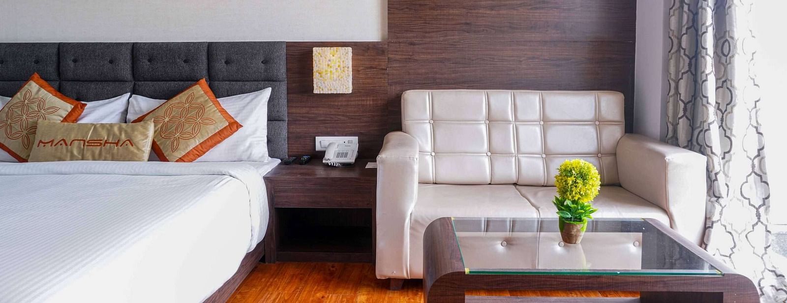 A room at Mansha Hotel Regency featuring a bed, a bedside table, a sofa, and a coffee table.