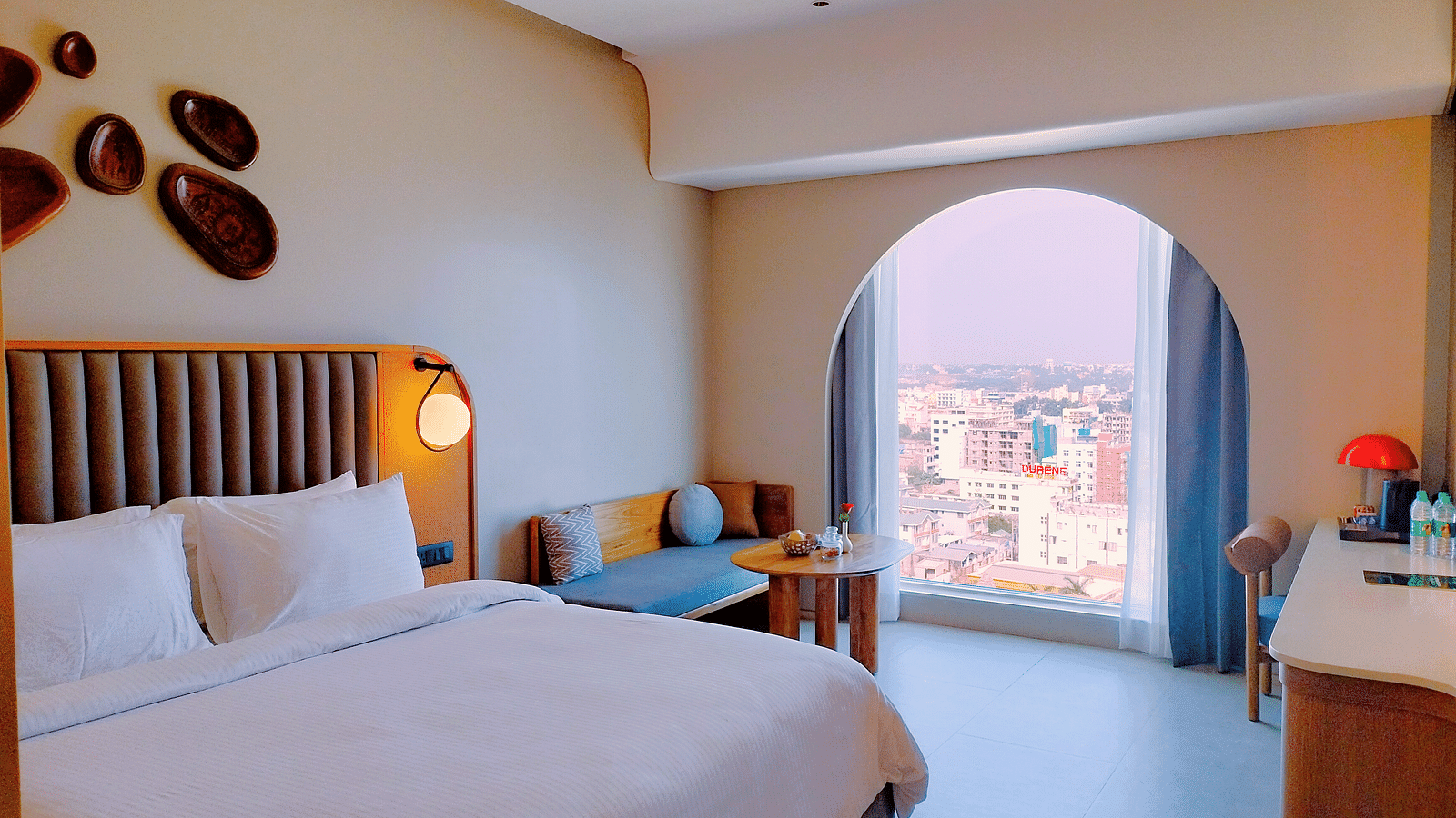 Sea view room at Swosti Premium Beach Resorts, Puri, featuring a made bed, decorative wall with unique design, stylish décor, and a ocean view from the window.