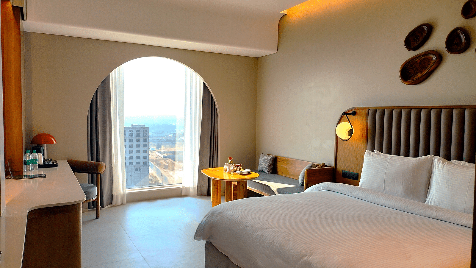 Sea view room at Swosti Premium Beach Resorts, Puri, featuring a made bed, an arched doorway to a balcony, and a ocean view.