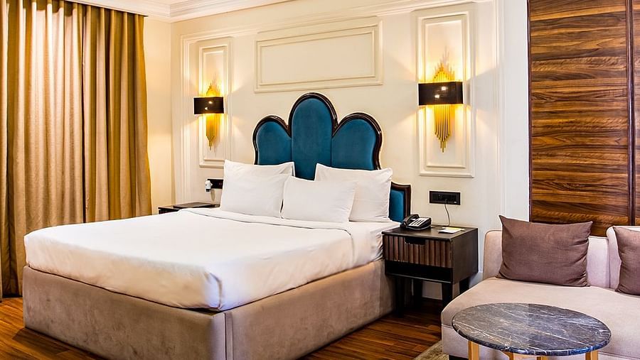 Luxurious hotel room with a king-sized bed and elegant decor with wooden panelled floors - Wedlock Greens Hotel & Resort, Dhanbad