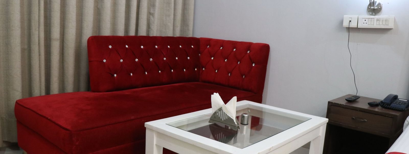 Sofa seating area adjacent to bed in guest room at Hotel Diamond Plaza, Chandigarh