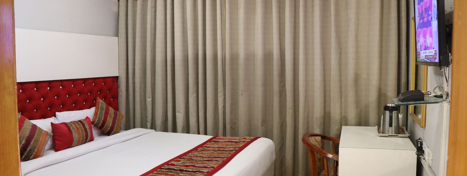Guest room with single bed, seating and drapes at Hotel Diamond Plaza, Chandigarh