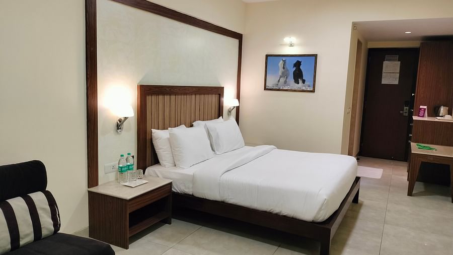 An image of Deluxe King Room featuring a bed, bedside table on either side, and a sofa - VITS Lonavla