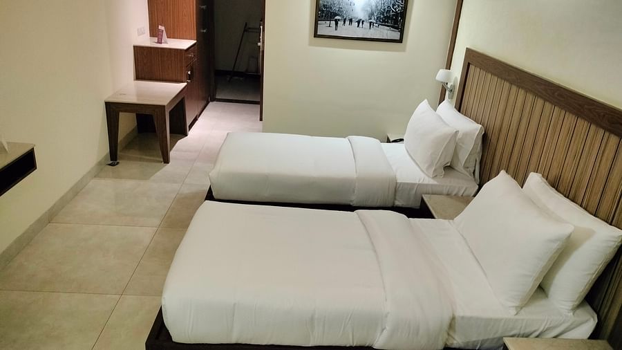 An image of a twin bed with a photo frame on the wall and a light is hanging from the ceiling - VITS Lonvala