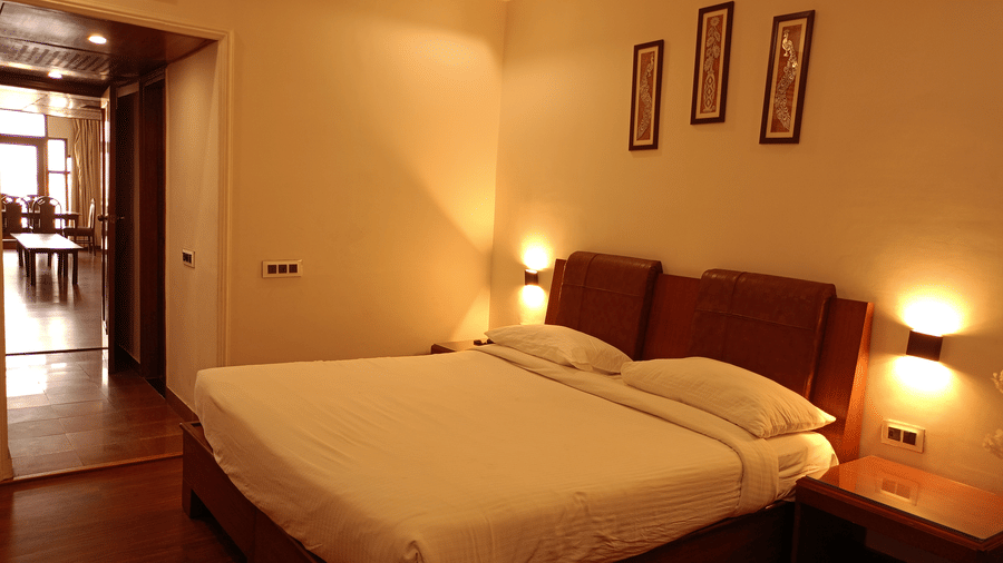 Guest room at Hotel Gold, Panipat featuring a bed, side tables, and framed wall art.