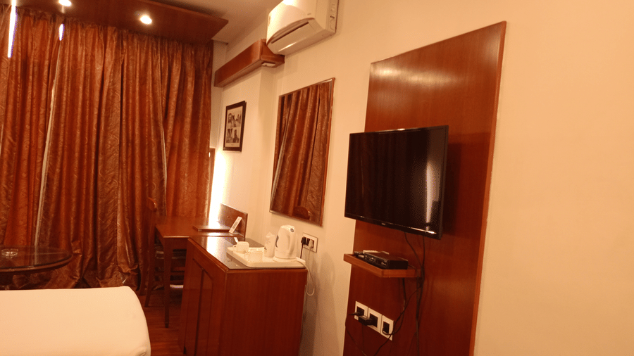 Room at Hotel Gold, Panipat with a bed, TV, desk, and curtains along the window.
