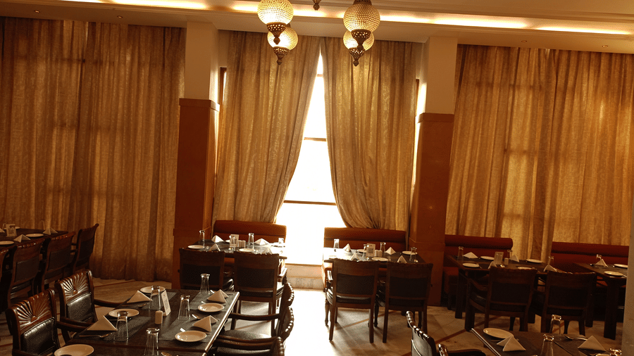 Restaurant at Hotel Gold, Panipat with arranged dining tables, chairs, and hanging lights.
