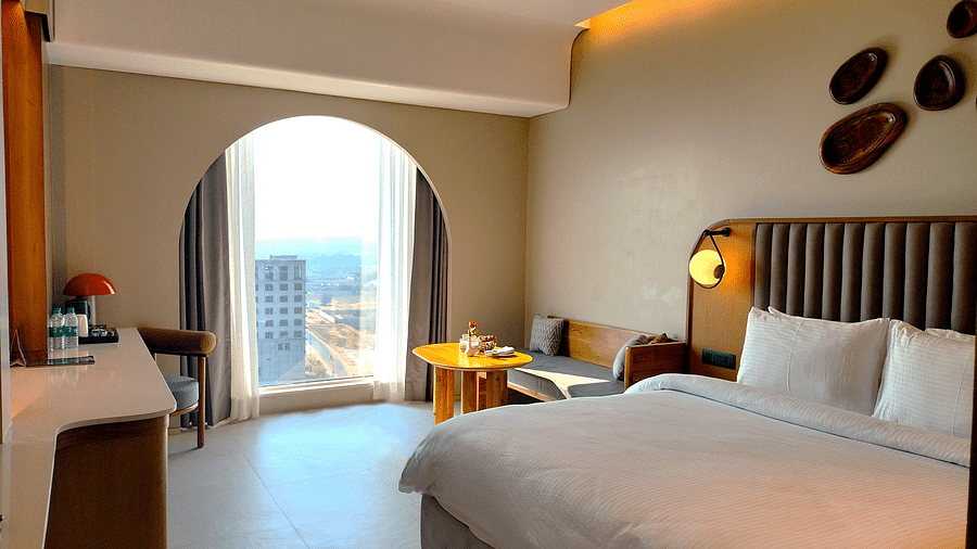 Sea view room at Swosti Premium Beach Resorts, Puri, featuring a made bed, an arched doorway to a balcony, and a ocean view.