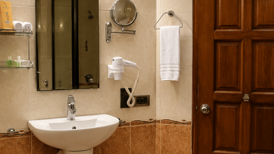 Bathroom with a pedestal sink, wall mirror, and warm ambient lighting at Chariot Beach Resorts, offering a comfortable guest experience.