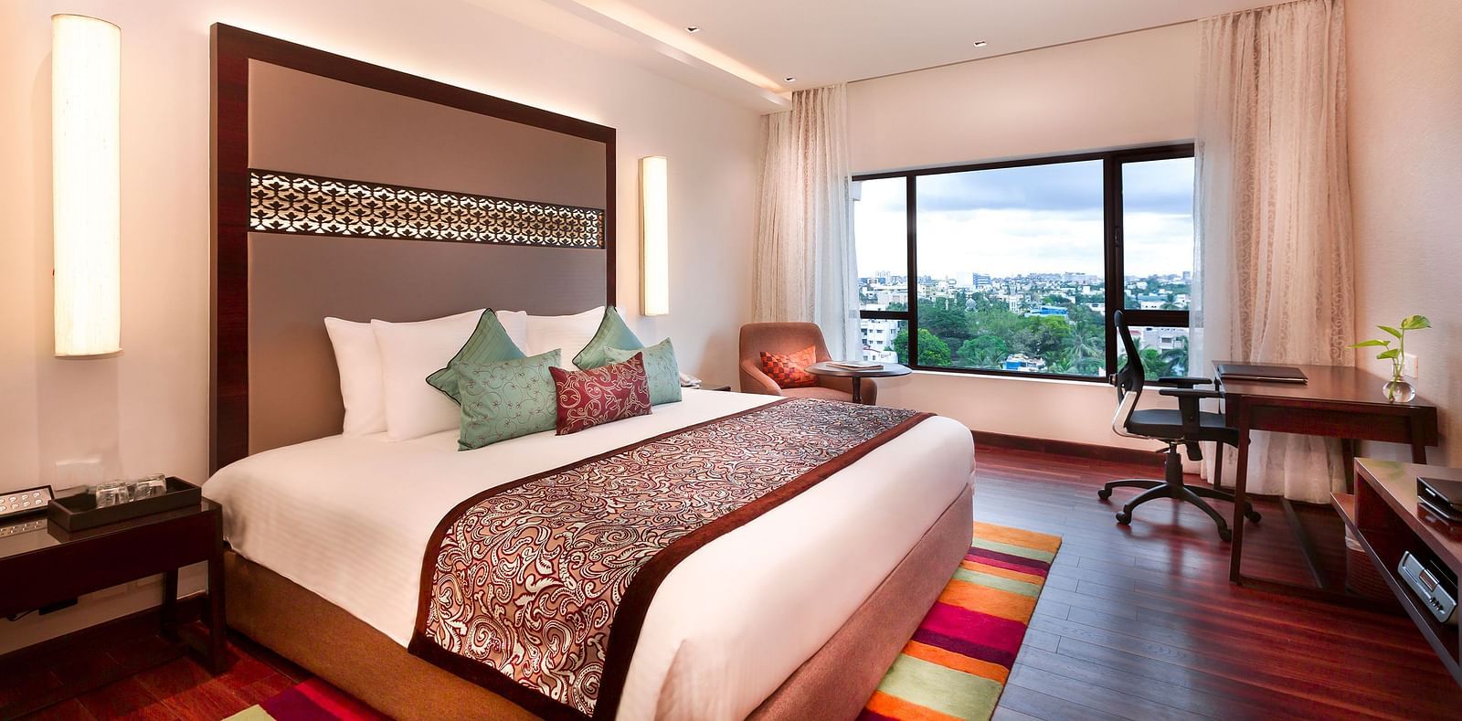 A spacious, well-lit hotel room at GRT Grand Chennai with a king sized bed and a large window overlooking the city. - Best hotel near U.S Consulate Chennai 