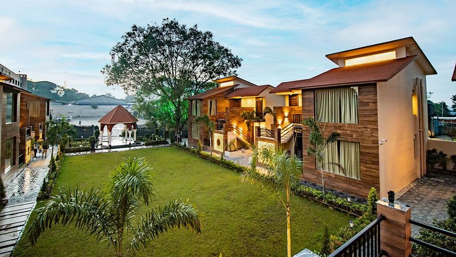 A scenic view of our hotel nestled near the lush lawn beneath the expansive open sky - Wedlock Greens Hotel & Resorts