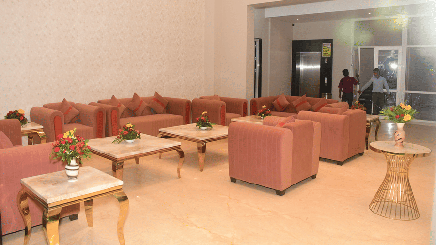A lobby area displays several pink armchairs, light wooden tables, and a neutral-toned wall - Kankidham Lords Inn