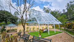 a green house in the centre with people sitting inside and greenery around it - Ibex Resorts