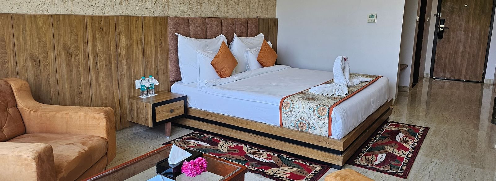 An interior shot of a hotel room at Bamboo Saa Mulberry Resort, with a bed, seating area, and a decorative rug.