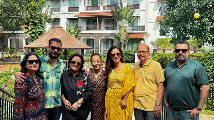 A group of people standing together in front of a building at Rhythm Lonavala, posing for a photograph with the structure clearly visible behind them as they gather on the walkway.