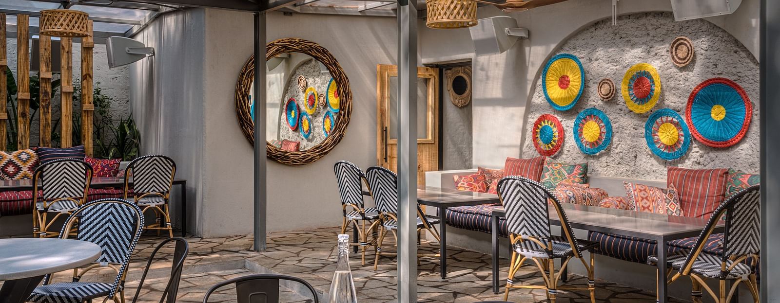 An overview of the outdoor seating arrangements with a mirror and handmade design on the wall at Village 36
