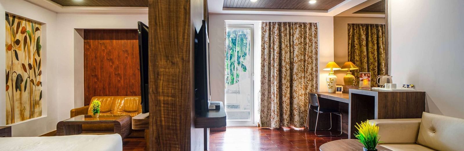 A room with a bed on side of the partition and the other side showcases a sofa, a coffee table, and more amenities at Mansha Hotel Regency.