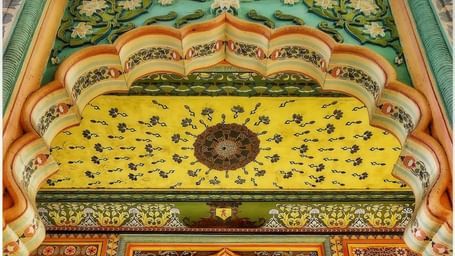 A long hall in an Indian palace is decorated with colourful, detailed arches and ornate traditional patterns.