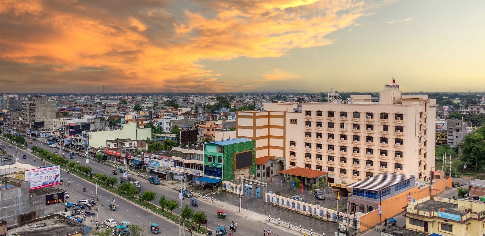 Aerial view of Diamond Palace Lords Plaza in Nepalgunj amidst a cityscape under a dramatic, colorful sky.