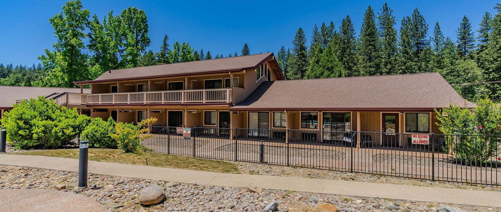 A view of a cabin at Amador Hotel with a forest in the backdrop on a clear, blue day.
