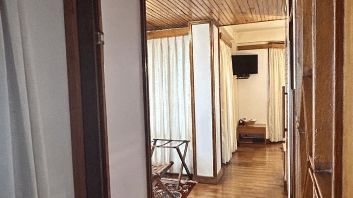 Hallway of the Executive Suite at Cedar Inn showing a wooden corridor with flooring, wall mirror, and a glimpse into the bedroom area.
