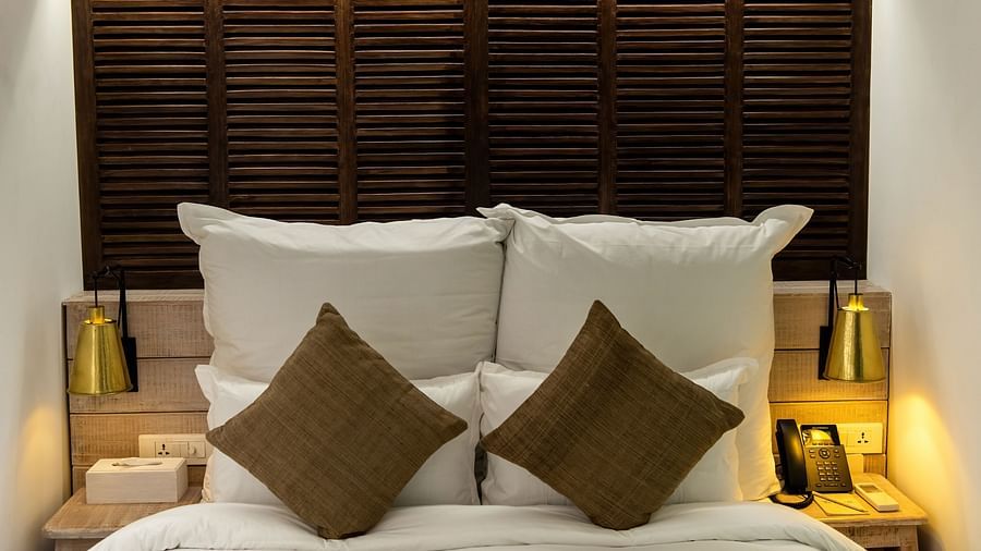 A room with a bed, pillows and cushions and bed side tables with lamps on either side - The Nanee