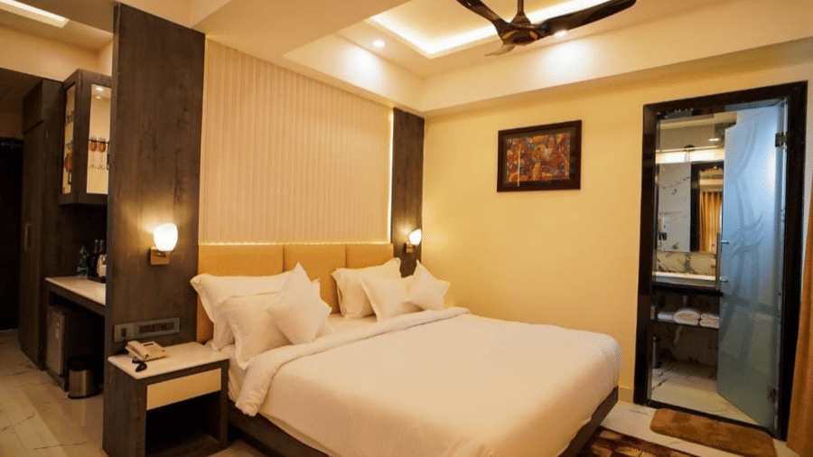 A corner view of the  bedroom showcasing plush bed with pillows, ceiling fan, artwork, and sliding balcony doors.